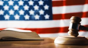 A wooden gavel sits on top of a book and an american flag.