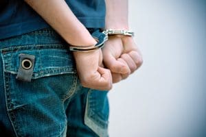 A young man with handcuffs on his hands.