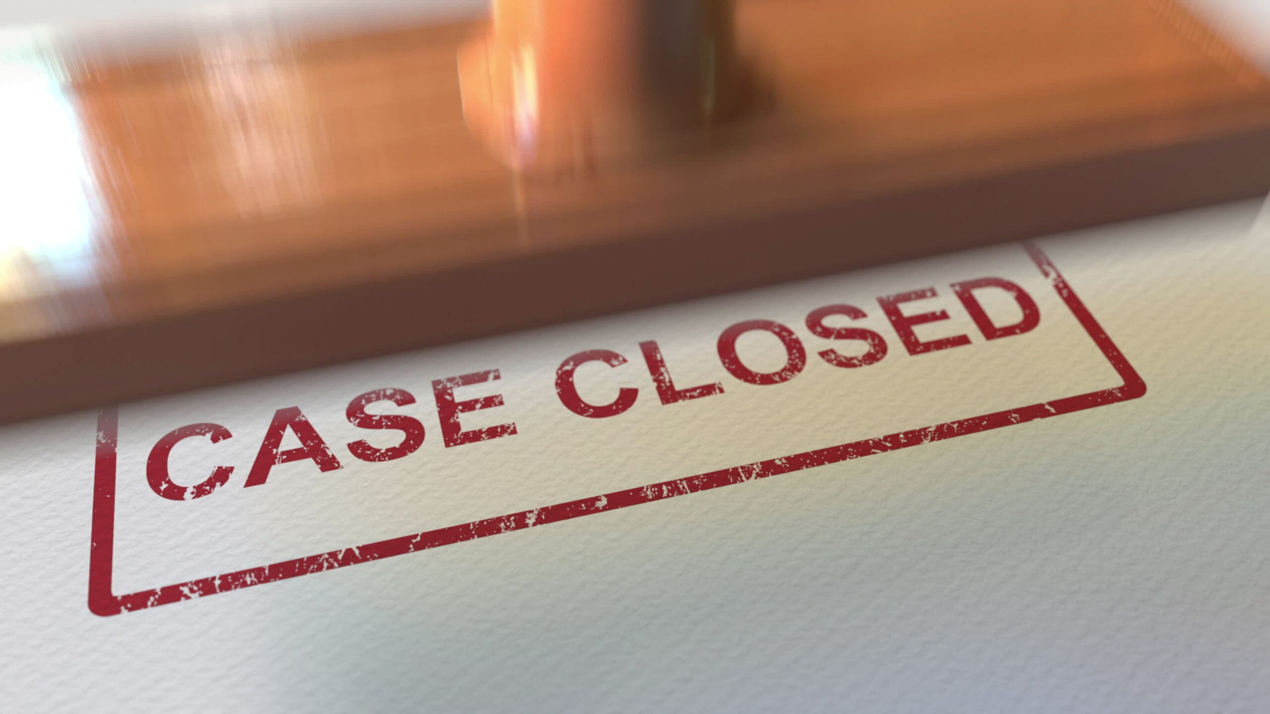 A close-up image of a rubber stamp marked "CASE CLOSED" in red ink on a piece of paper. The stamp is slightly worn, giving a slightly textured appearance to the text. The background is a plain, white surface.